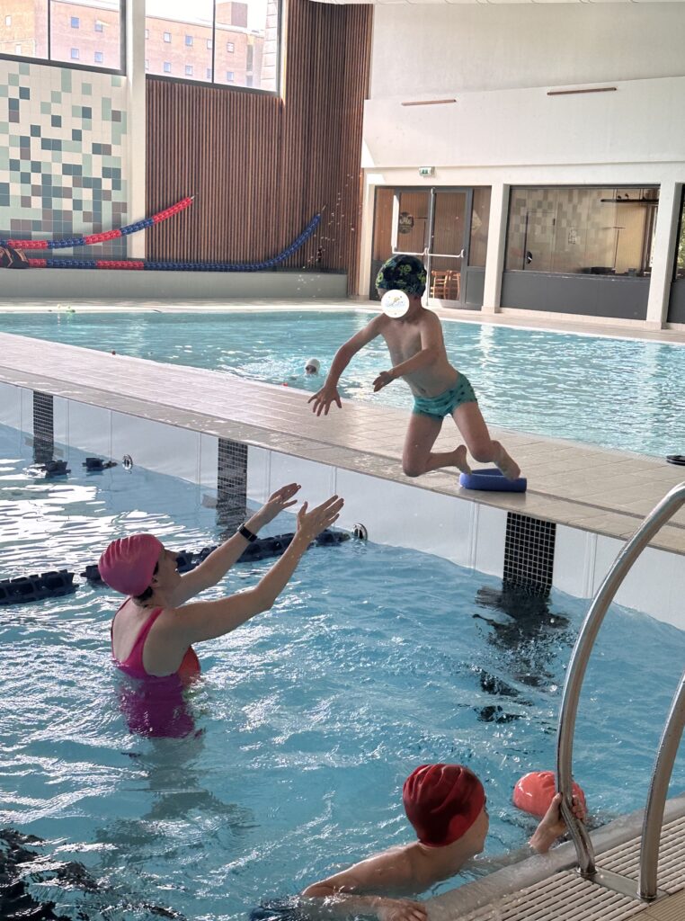 Annabelle réceptionne un enfant lors d’un saut durant son cours de natation à Bastogne.